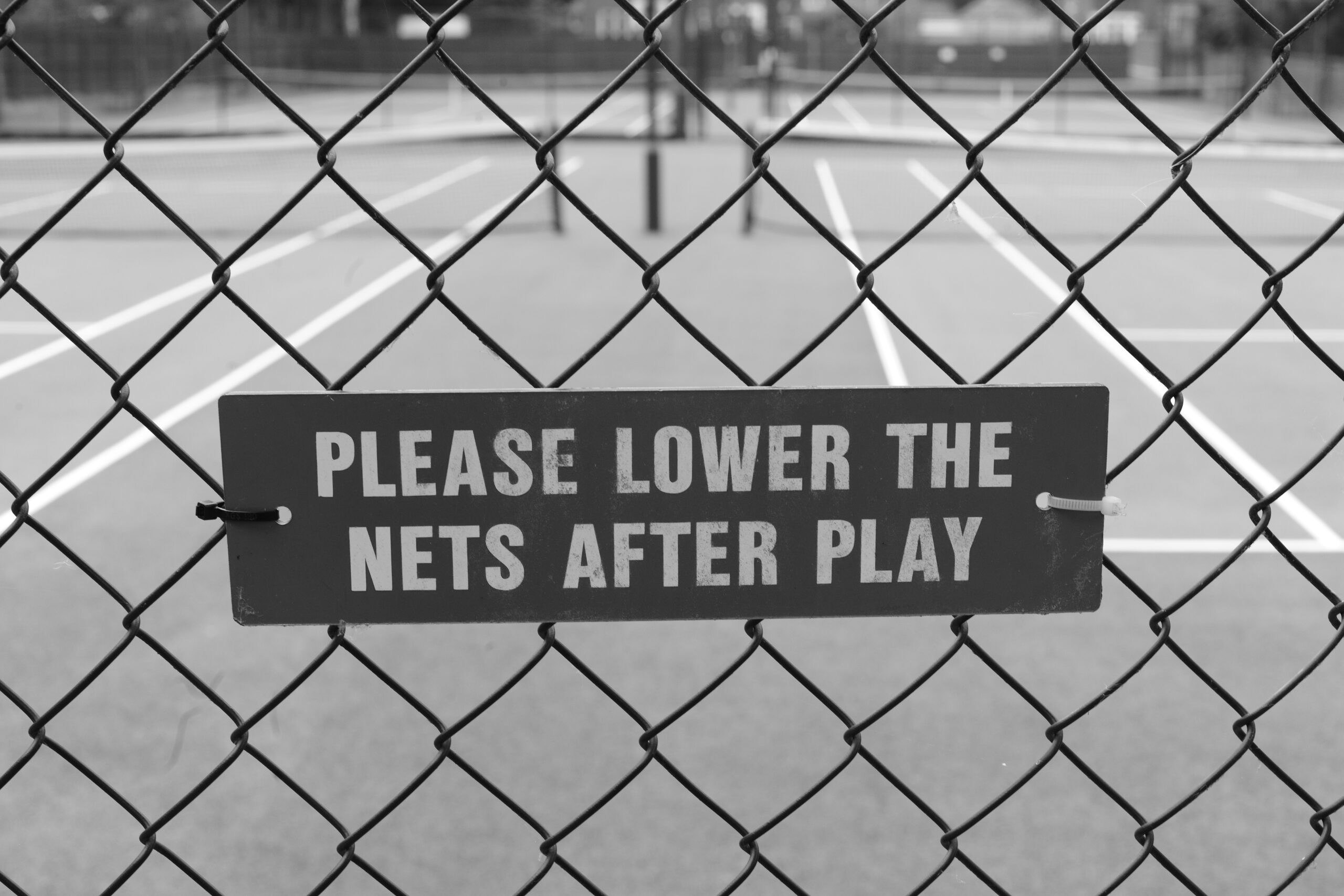 Sign on fencing saying Please Lower Nets After Play.