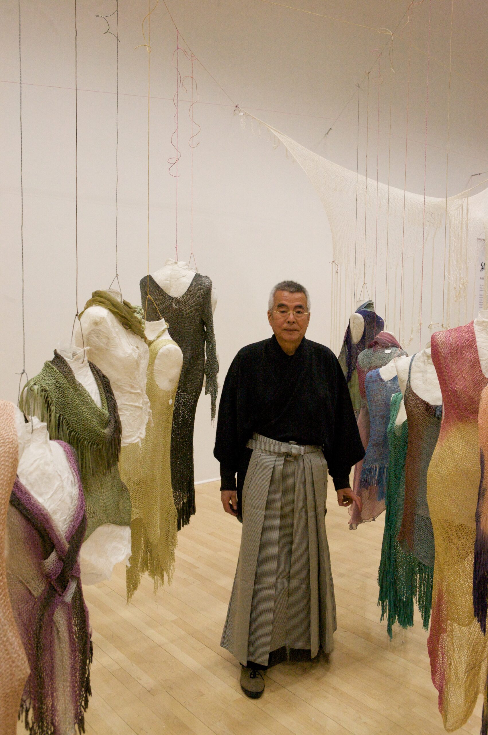 Artist Akihiko Izukura walks between two rows of his dresses.
