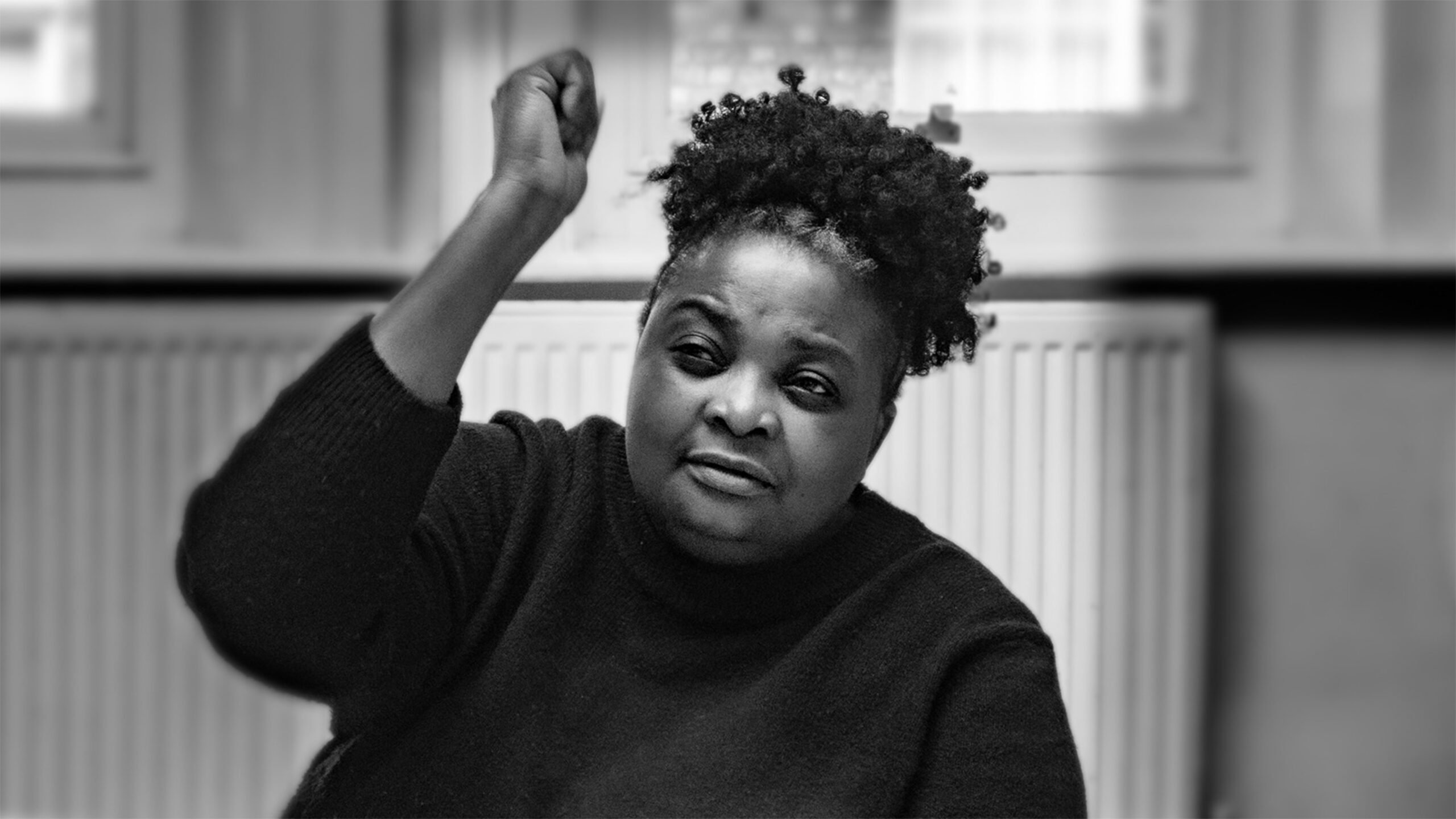 A black and white image of a woman with her left hand in the air.