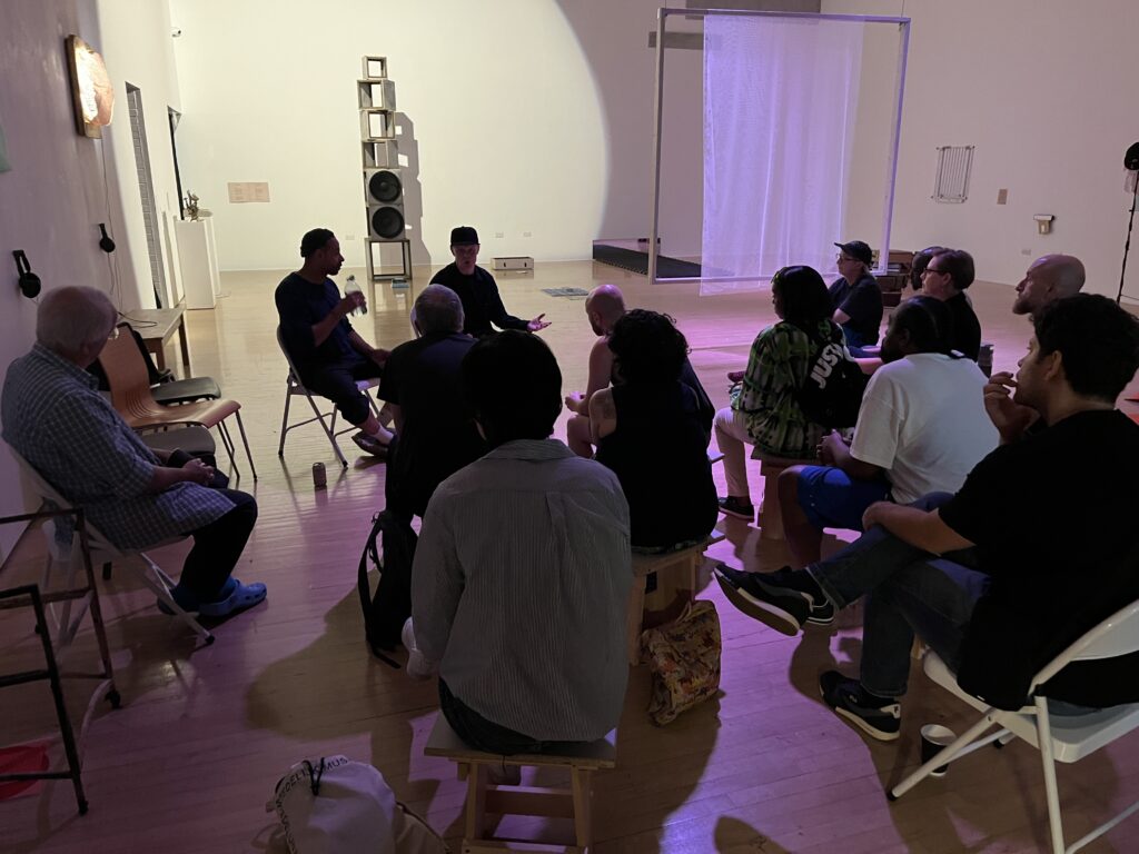 Tom Harris and Paul Adey (Cappo) sat on chairs in the gallery in discussion in front of an audience of around 20 people.