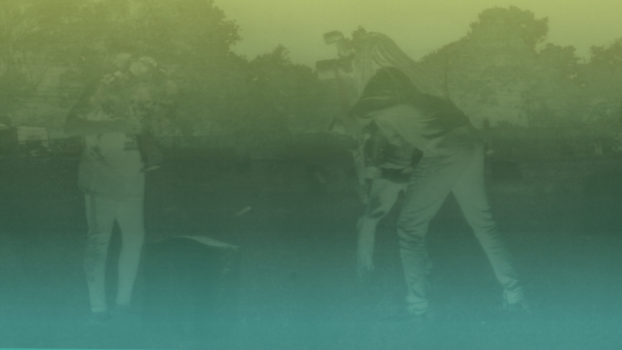 A distorted image of two figures in front of a gravestone in an green ombre - like a photographic negative.